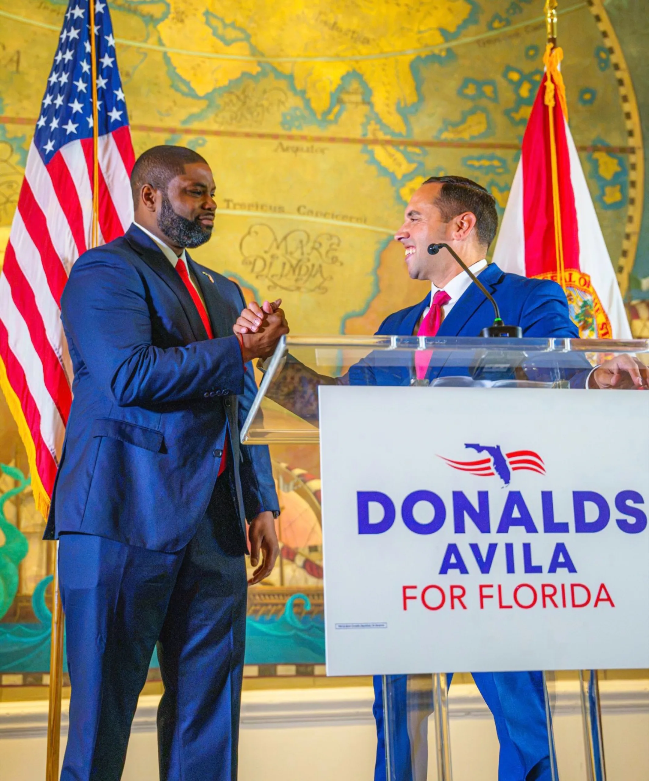 Byron Donalds and Bryan Ávila shaking hands at a Donalds Ávila for Florida podium